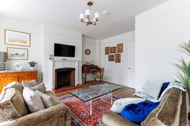 Shared lounge at Consorts & Concubines, with sofas, a fireplace, artwork and a writing desk.